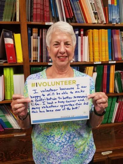 Literacy Services Volunteer holding "Why I Volunteer Sign".